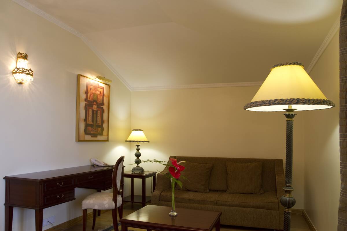 Una habitación con escritorio, silla, lámpara y sofá.