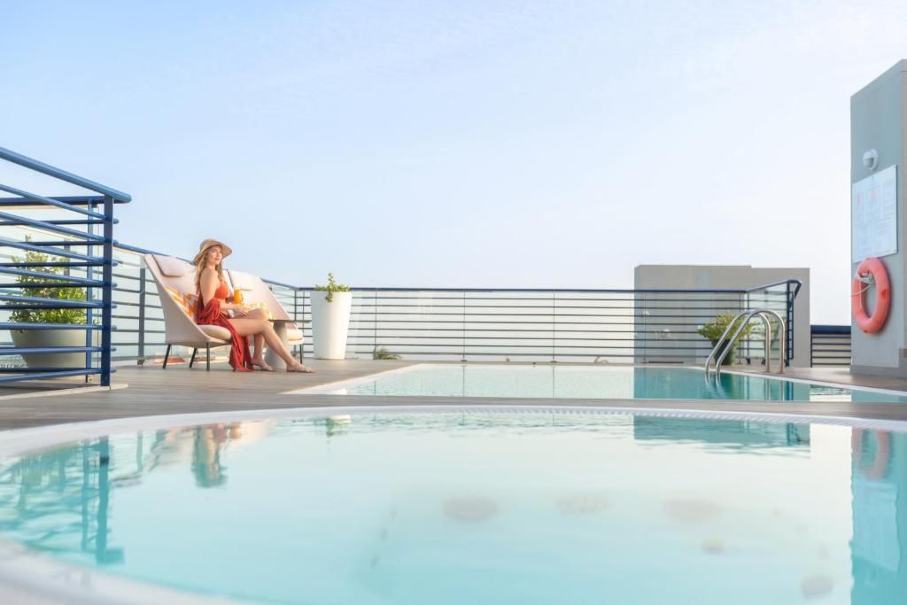 Una piscina al aire libre, sombrillas, sillones reclinables de piscina