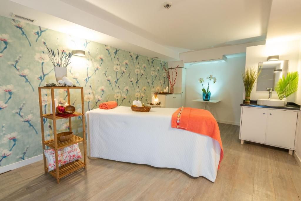 A room with a bed, a wooden shelf with towels, a small table with candles, and a mirror.