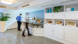 A modern kitchen with a buffet setup, white cabinetry, and a patterned backsplash.