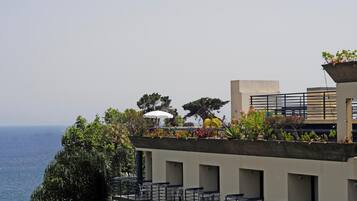 Eine Dachterrasse mit Sitzgelegenheiten im Freien, Blick aufs Meer und einem Blumentopf.