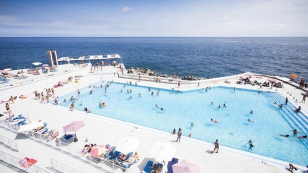 A large pool area on a cruise ship with multiple swimming areas and sun loungers.