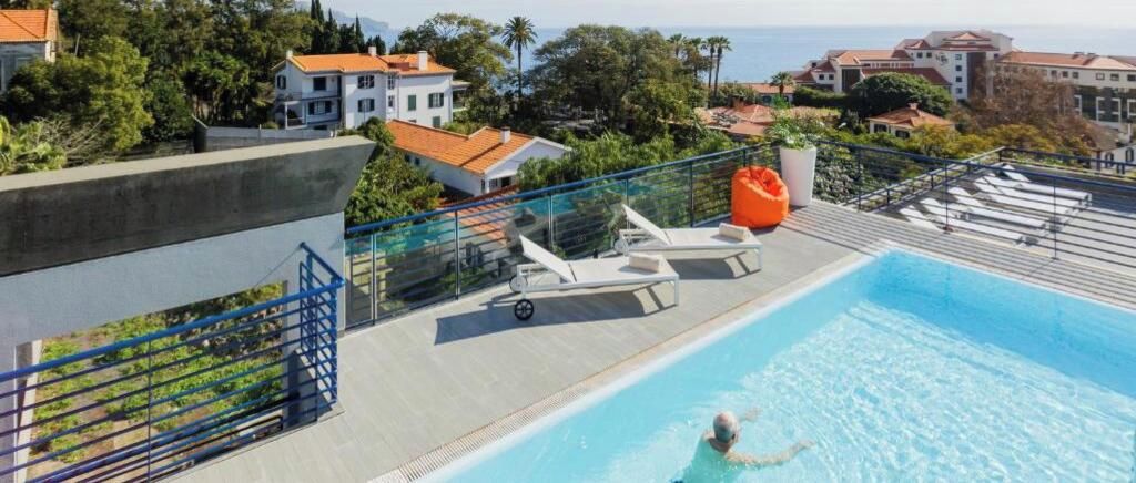 Una piscina con sillones de descanso y vista al mar.