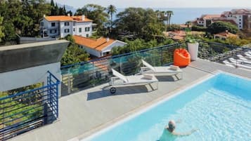 A swimming pool with lounge chairs and a view of the sea.