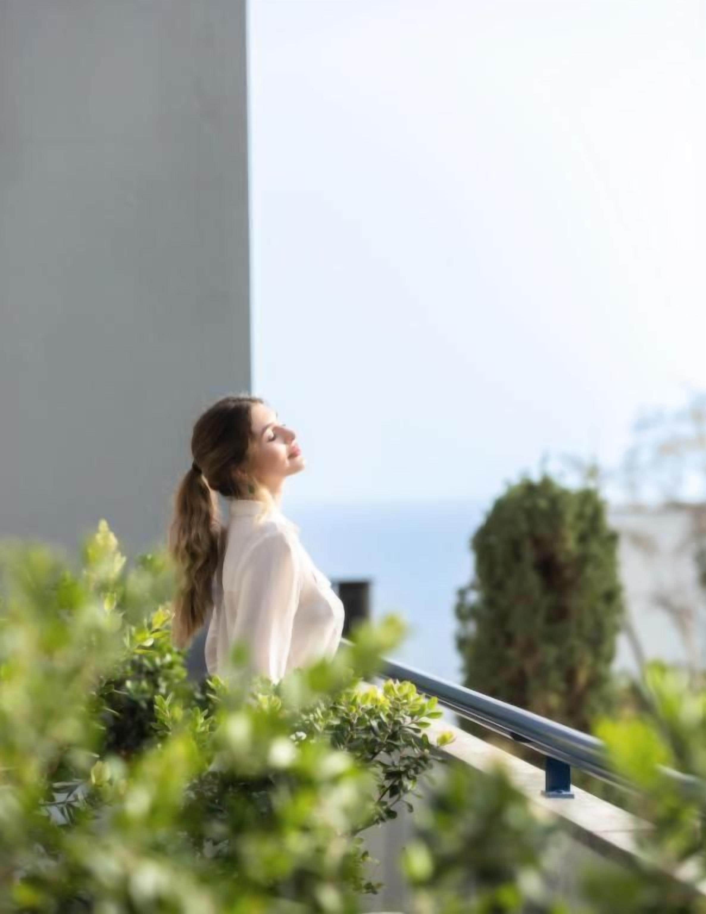 A person standing on a balcony with a view of the sea.