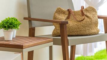 Una silla de madera con un bolso tejido encima, una planta pequeña en maceta y una mesa con superficie de color claro.