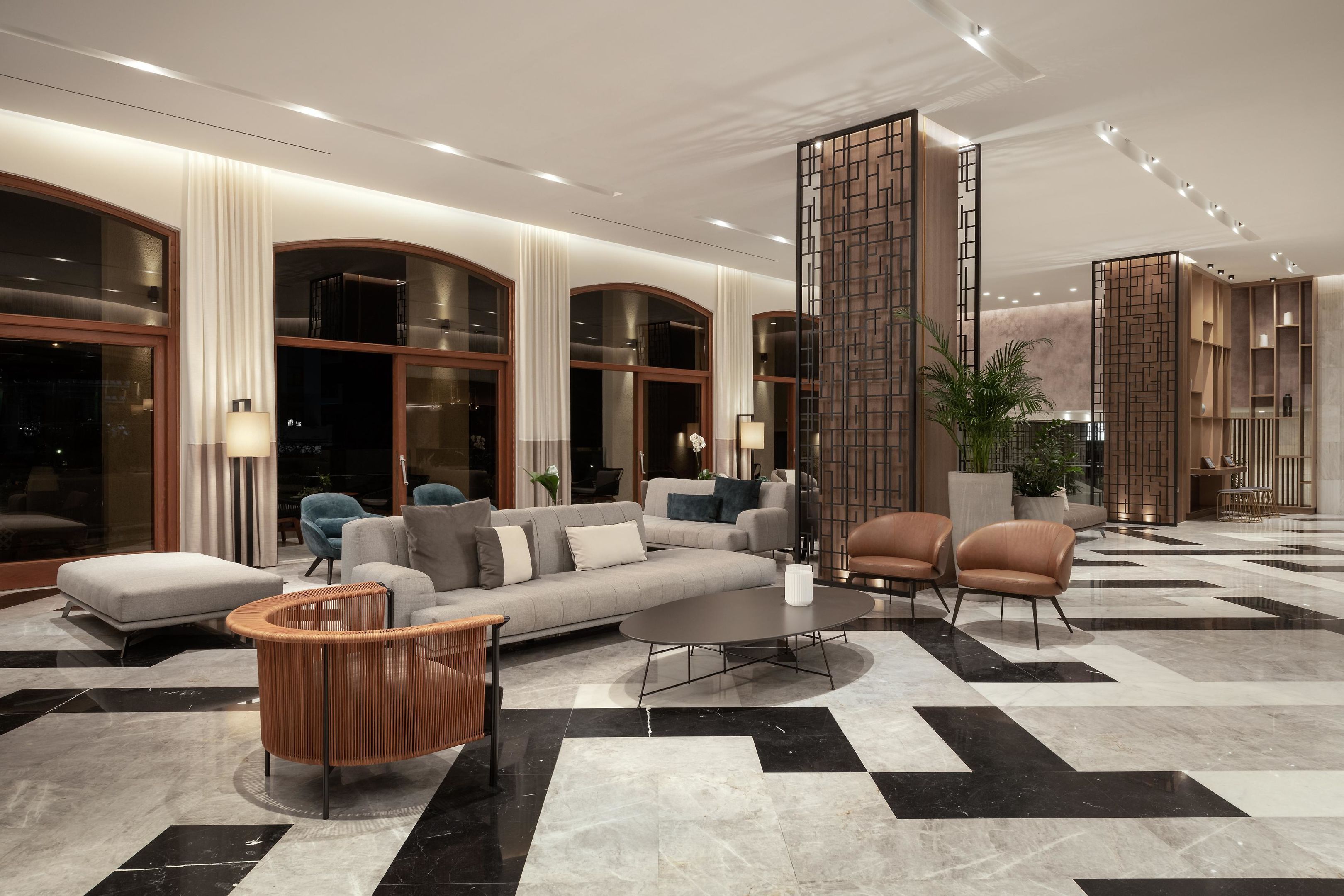 Un hall d’entrée moderne avec un canapé modulable, des fauteuils, une table basse et un paravent décoratif en bois.