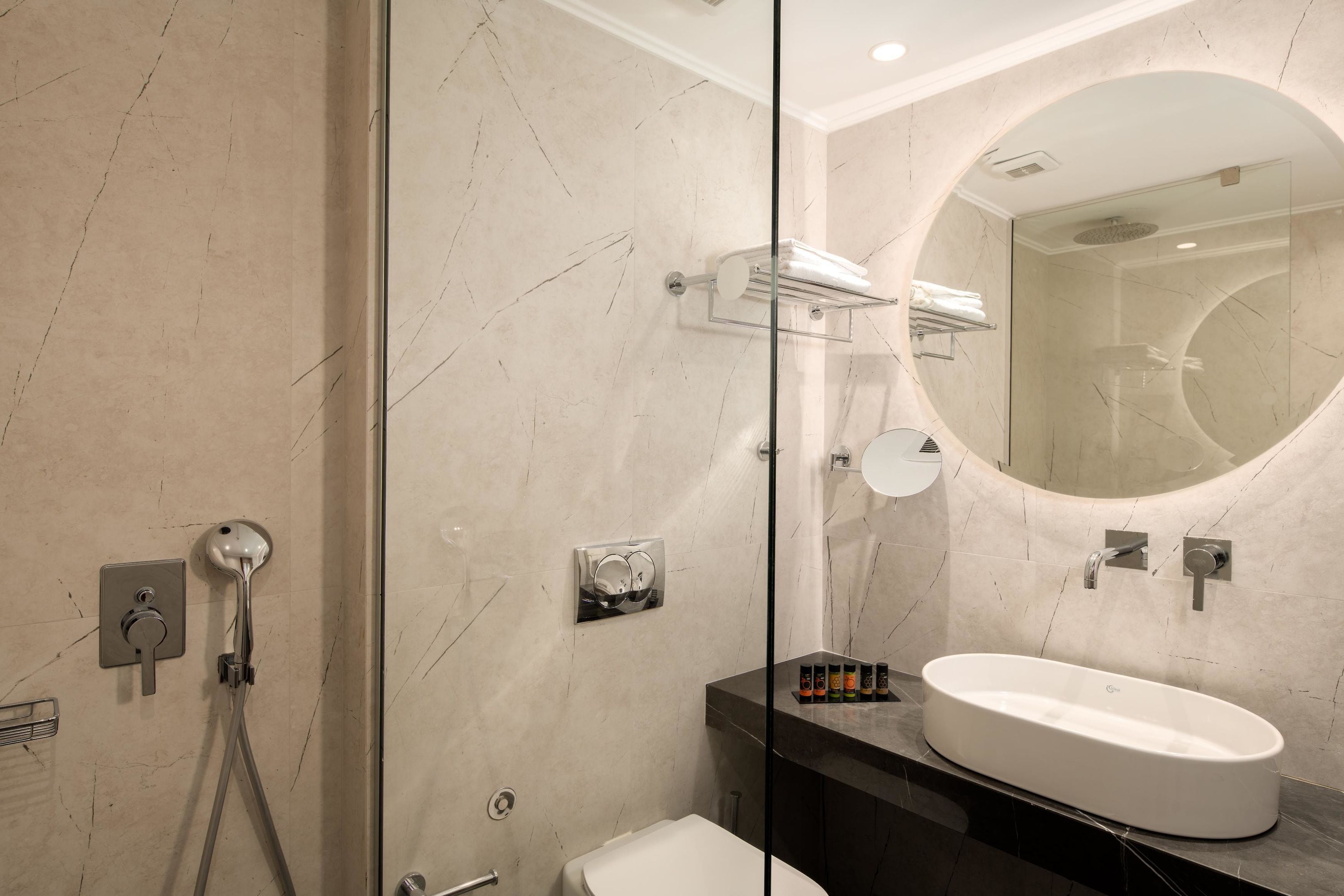 Ein modernes Badezimmer mit einer begehbaren Glasdusche, einem weißen Waschbecken und einem großen Spiegel.