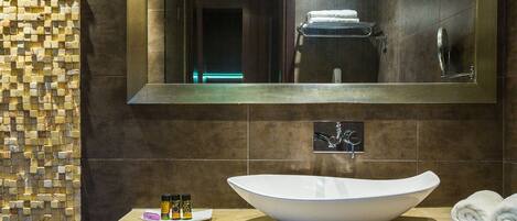 A modern bathroom with a large mirror, a vessel sink, and a towel rack.