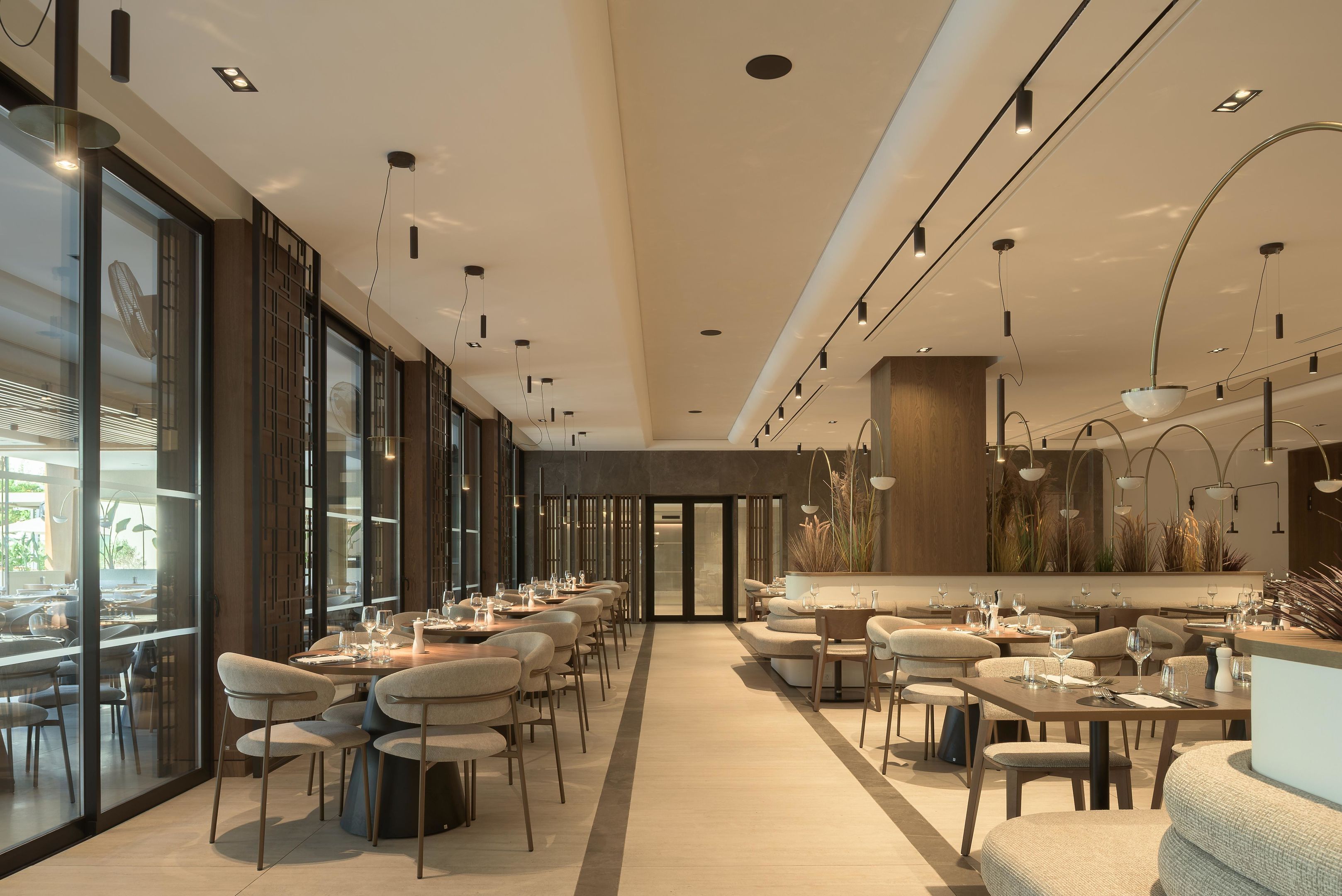 Interior de restaurante moderno con techos altos, iluminación colgante y una zona de estar central.