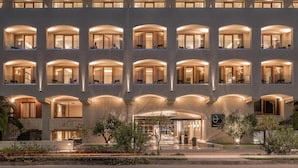 A multi-story hotel with a modern design, featuring balconies with glass railings and warm lighting.