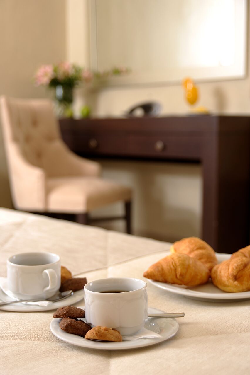A breakfast setting with two cups of coffee, croissants, and cookies on a table.