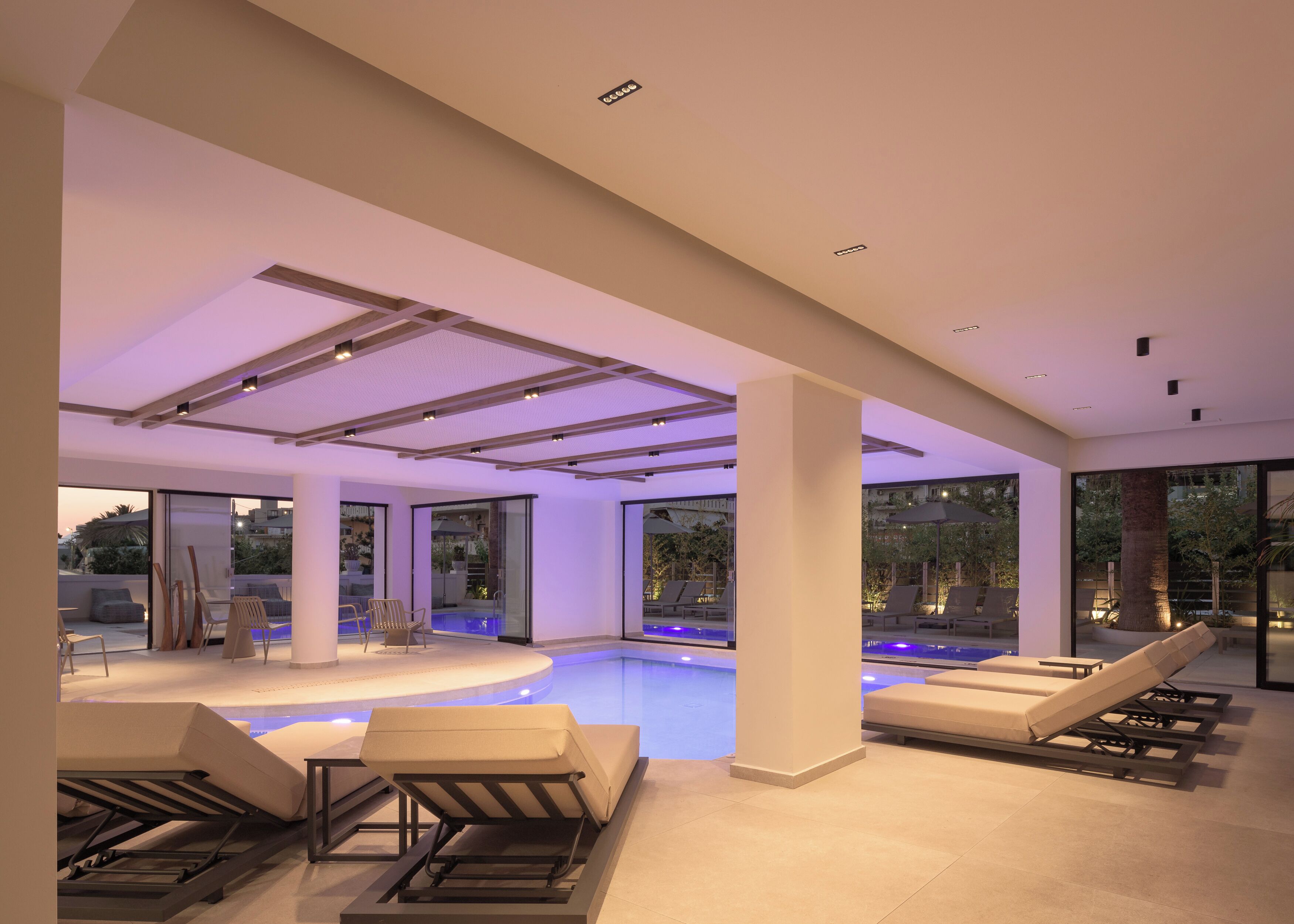 A modern indoor pool area with lounge chairs and a glass-enclosed pool.