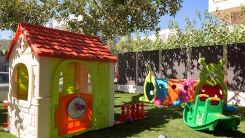 A children's play area with a small house, slides, and climbing structures.