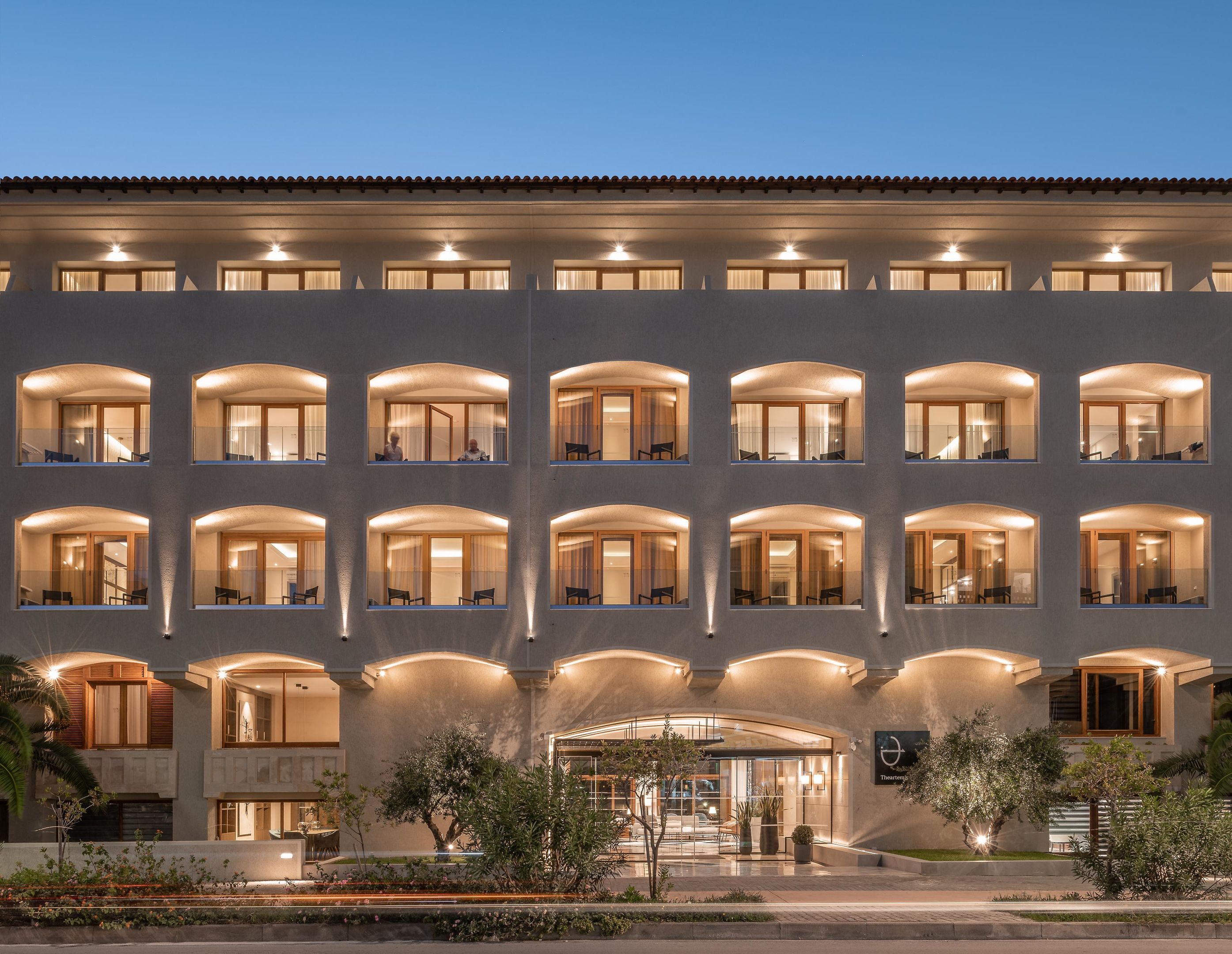 Un hotel de varios pisos con ventanales arqueados y una entrada central.