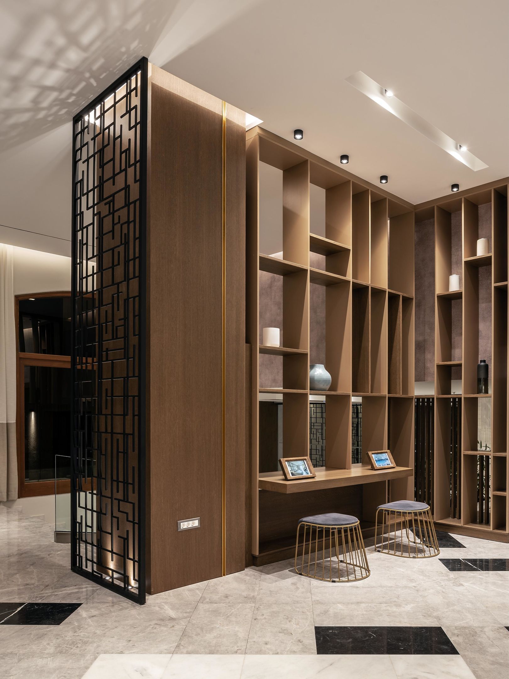 Een modern interieur met een ingebouwde boekenkast, een bureau met twee stoelen en een decoratieve scheiding.