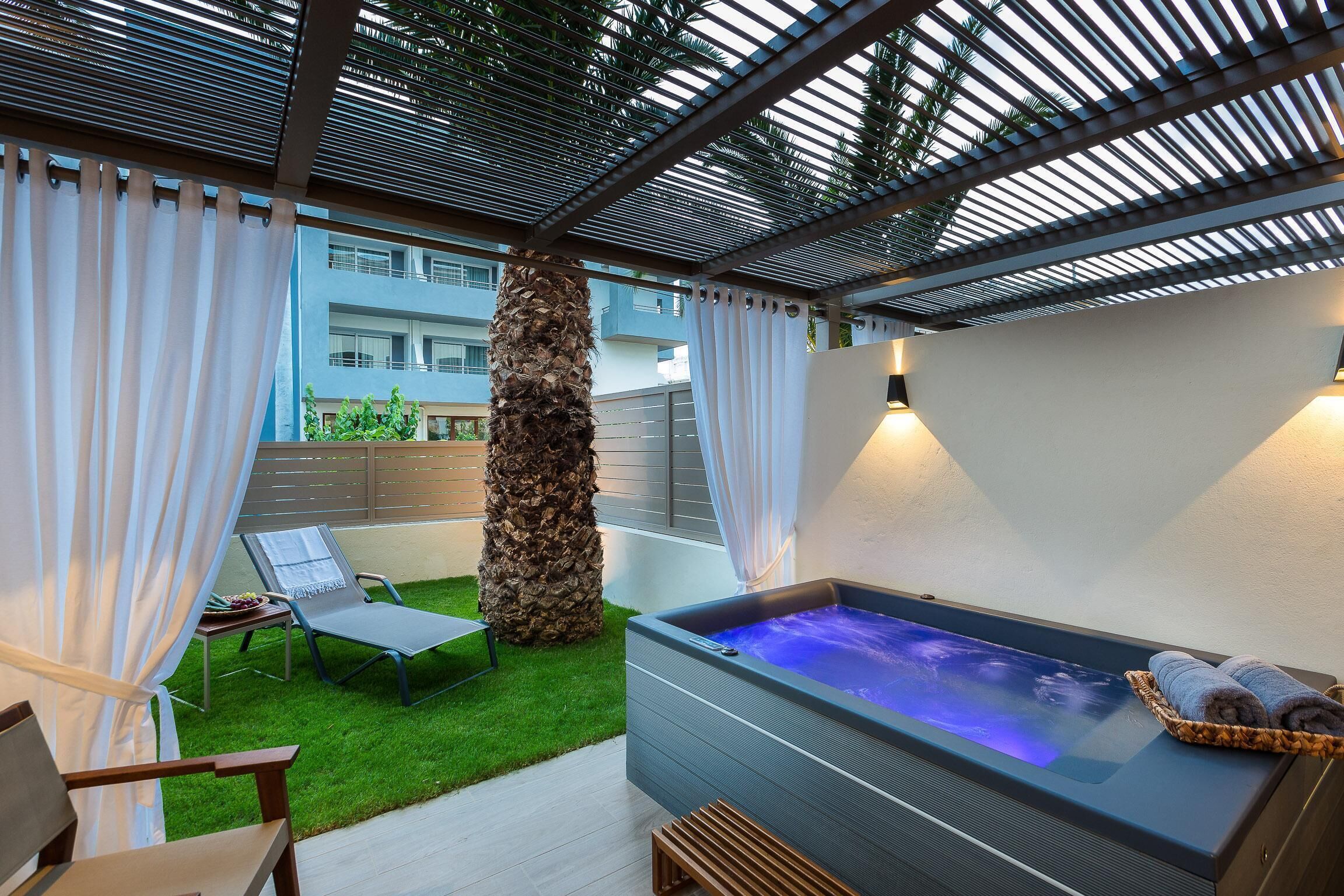A spa area with a hot tub, lounge chairs, and a palm tree.