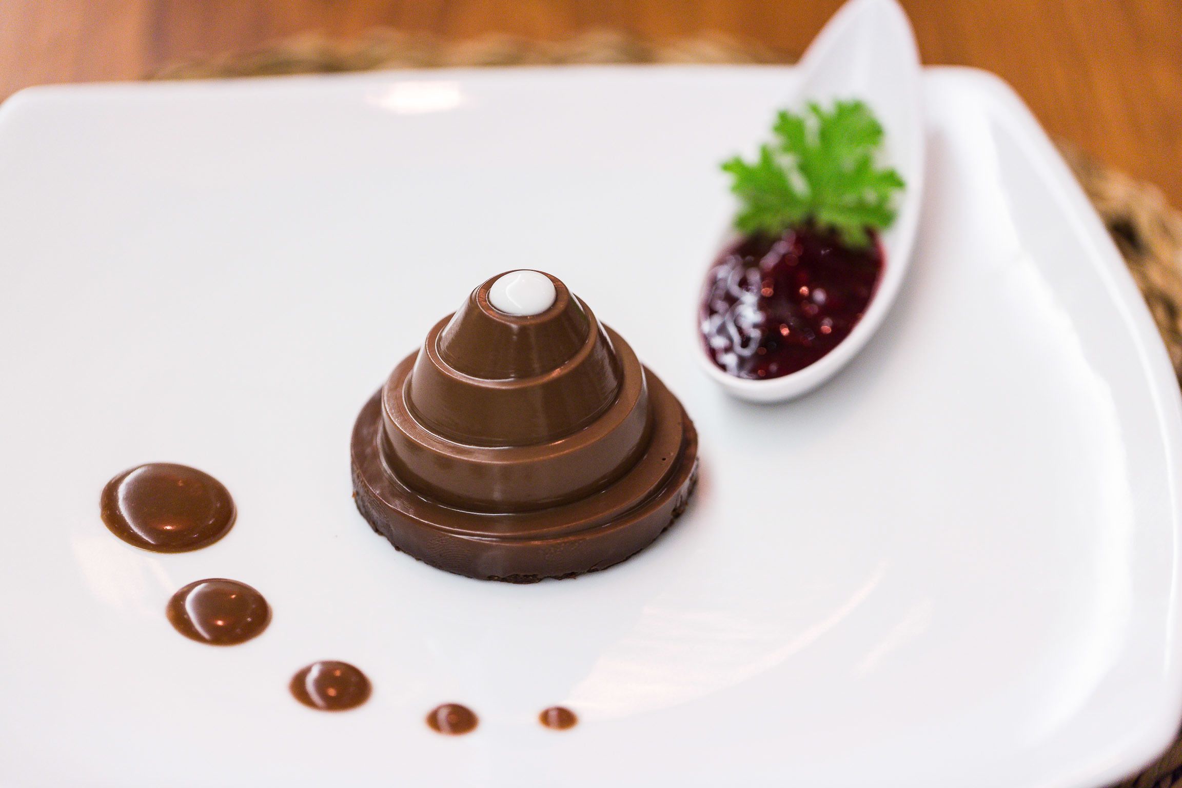 Un dessert servi dans une assiette blanche, accompagné d’une cuillère et d’une garniture.