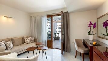 A modern living room with a sofa, armchairs, a small table, and a balcony with potted plants.