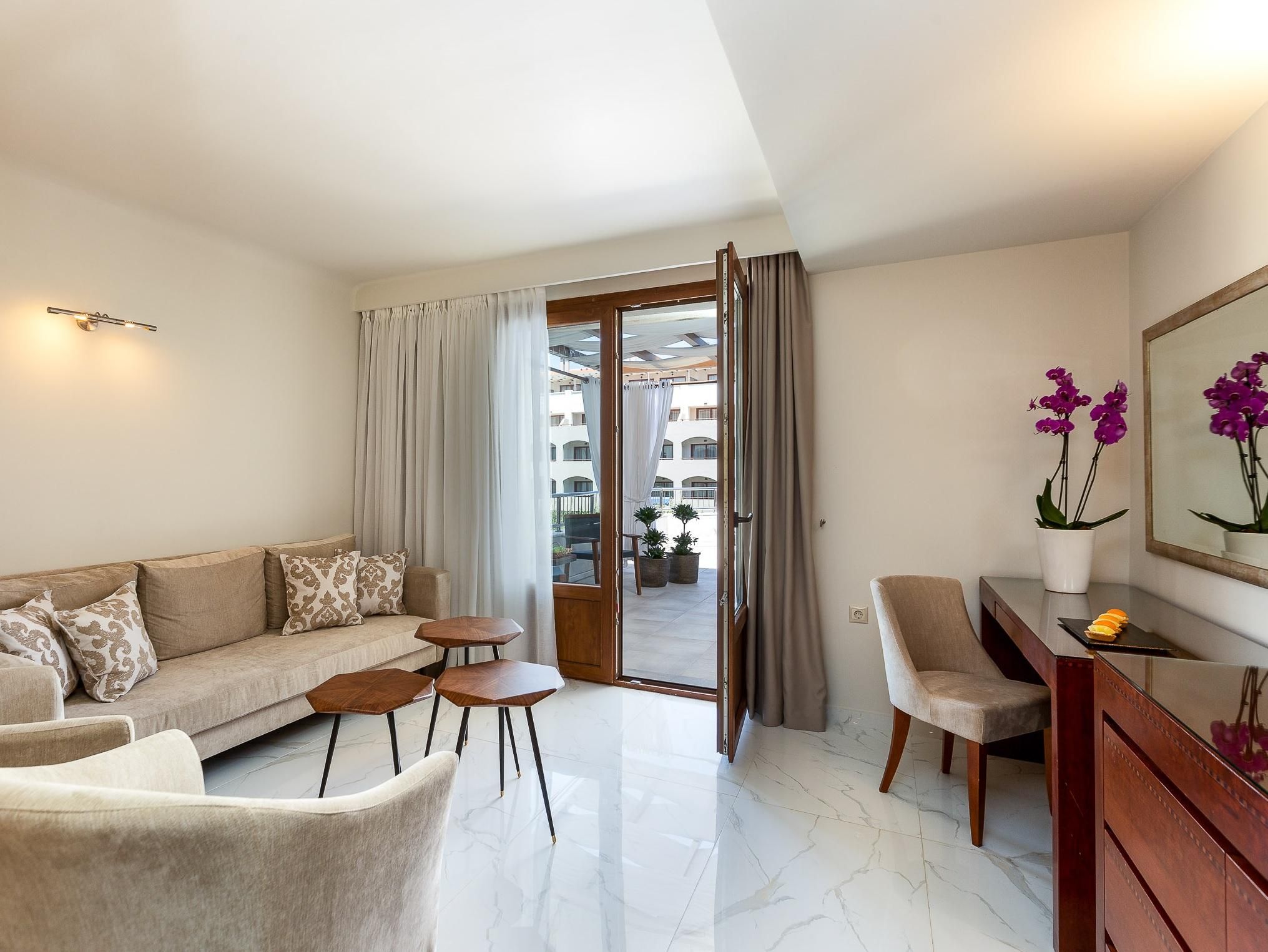Un moderno salón con un sofá, dos sillones, una mesita, un aparador de madera y una orquídea en maceta.