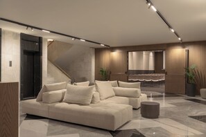 A modern lobby with a sectional sofa, a staircase, and a seating area with chairs. - Theartemis Palace (Rethymno)