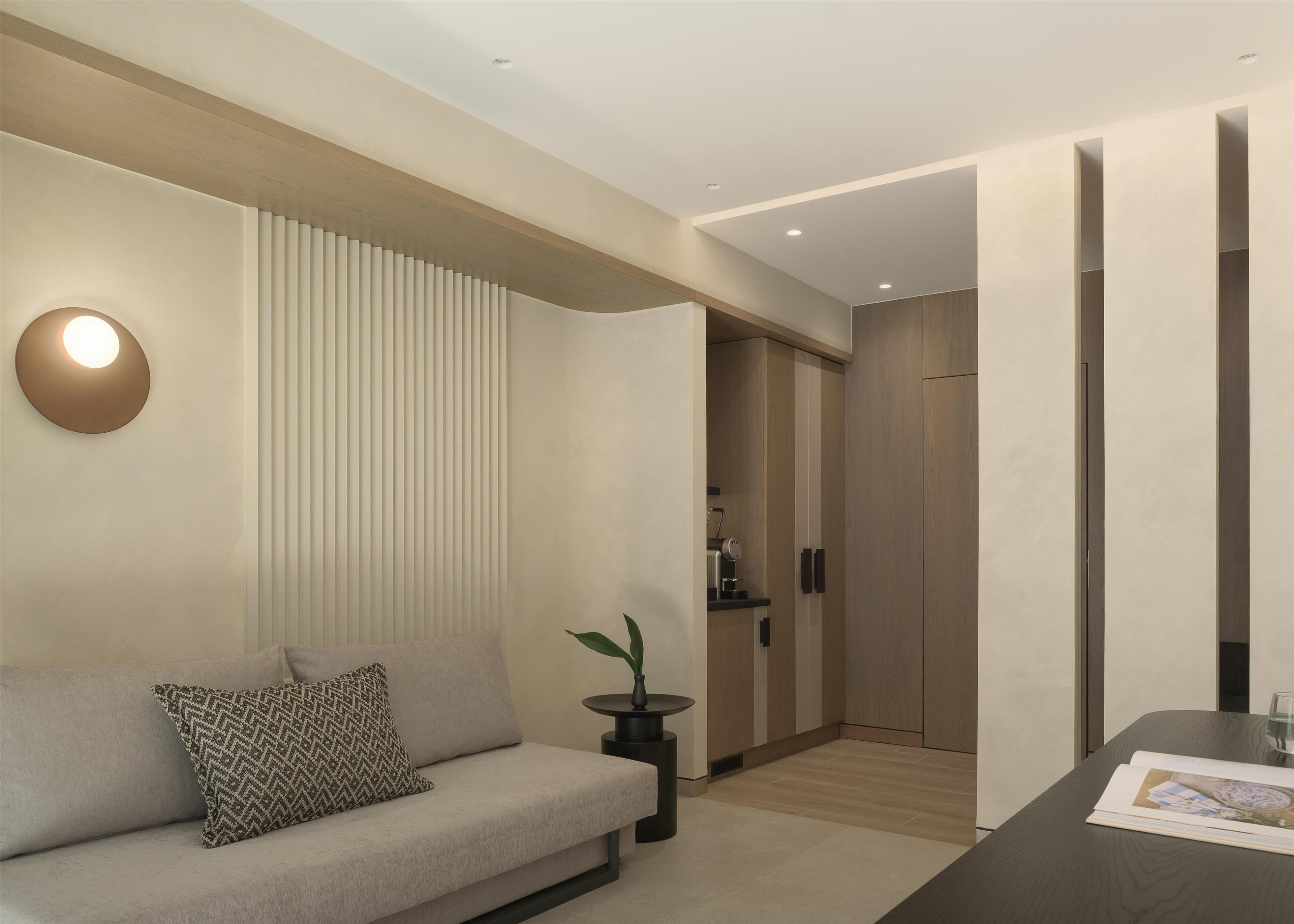 Una sala de estar moderna con un sofá, una mesita auxiliar con una planta y una zona de cocina con armarios y una encimera.