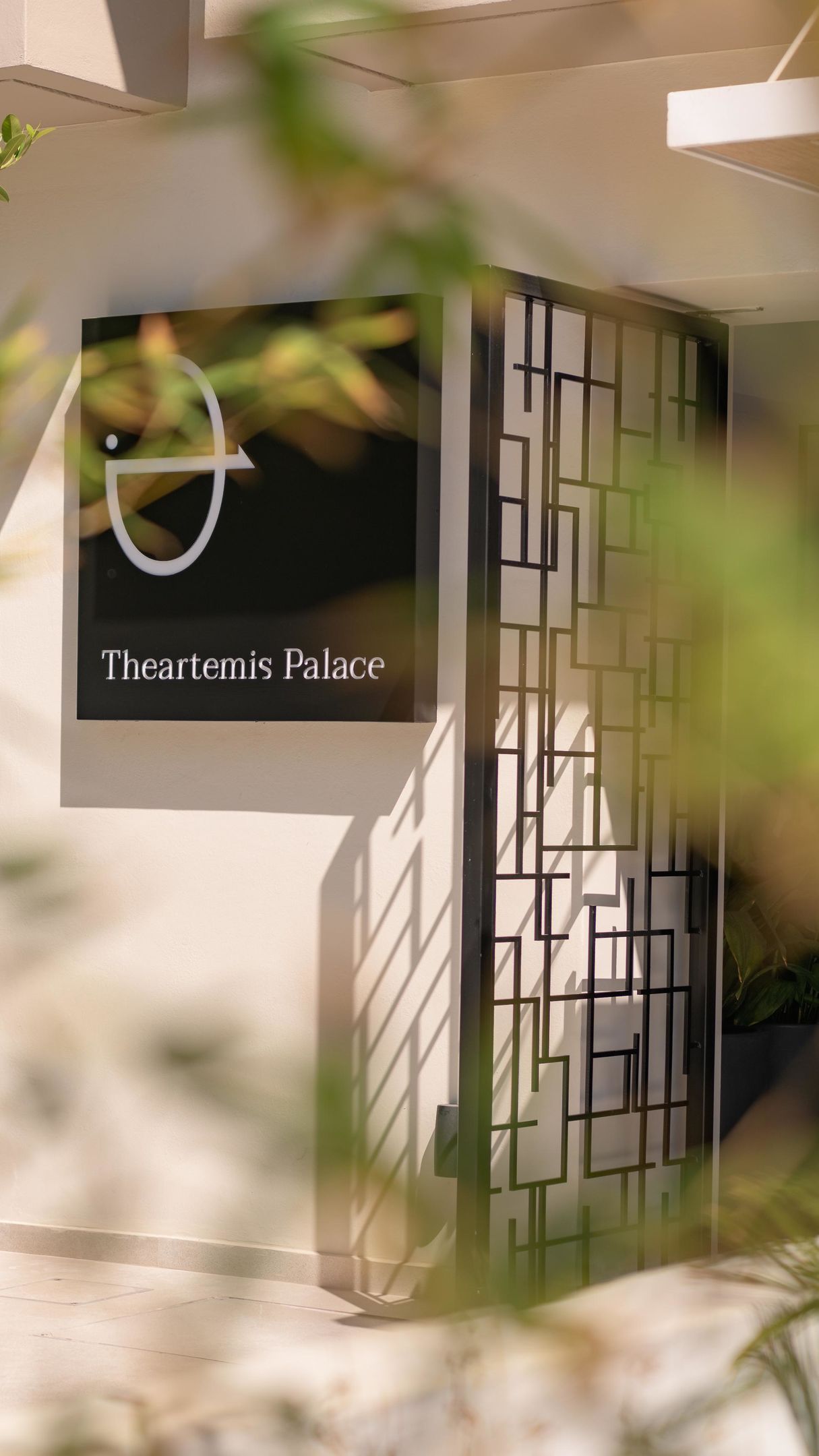 A modern building facade with a geometric pattern and a sign that reads 'Theartemis Palace.'