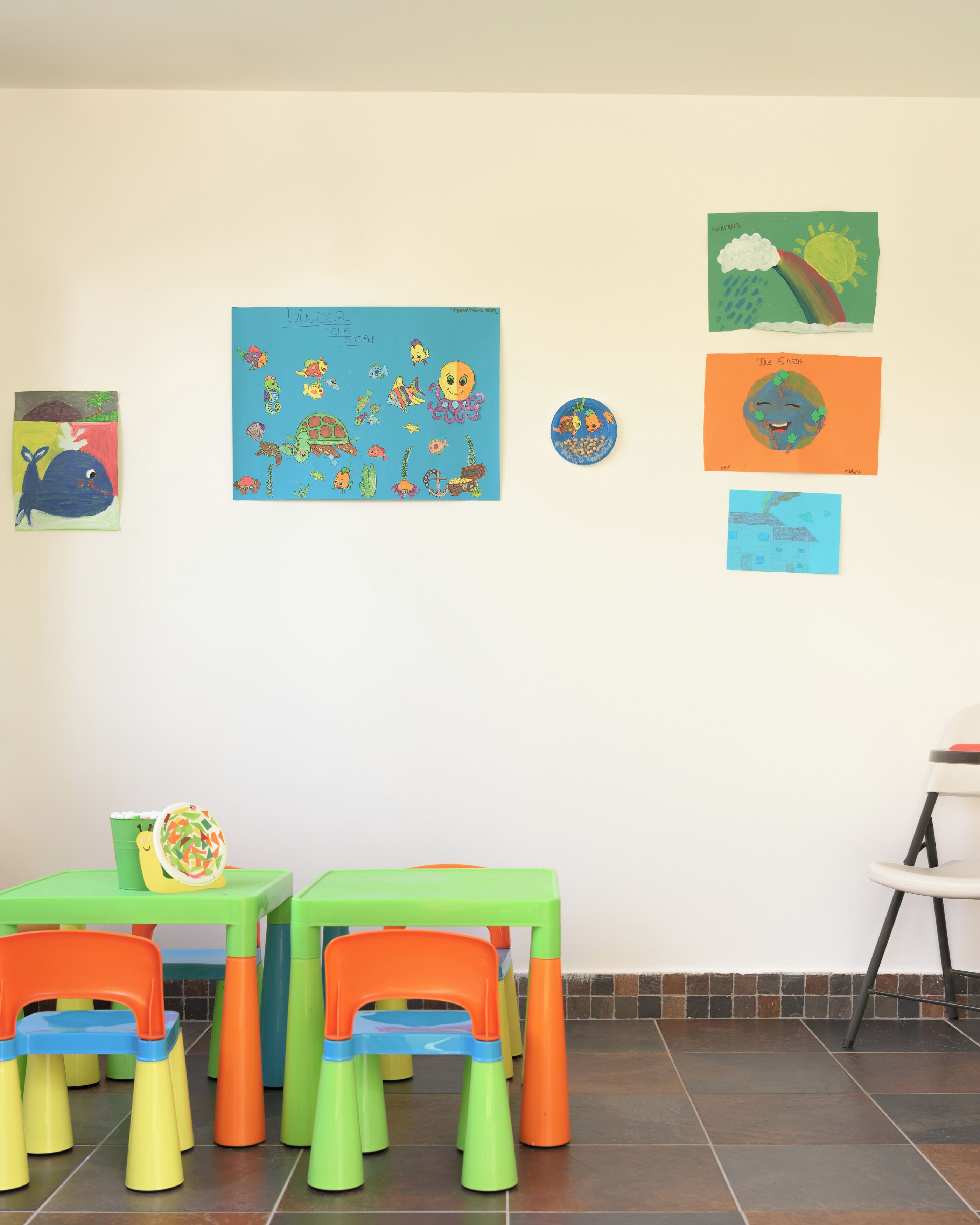 Un cuarto de juegos infantil con muebles coloridos y obras de arte educativas en las paredes.