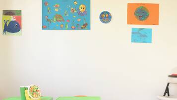 Un cuarto de juegos infantil con muebles coloridos y obras de arte educativas en las paredes.