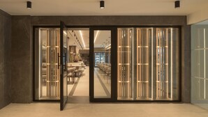 A modern hotel lobby with a glass door leading to a dining area.