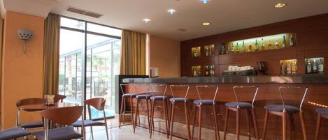 A bar area with multiple stools and a counter with bottles.