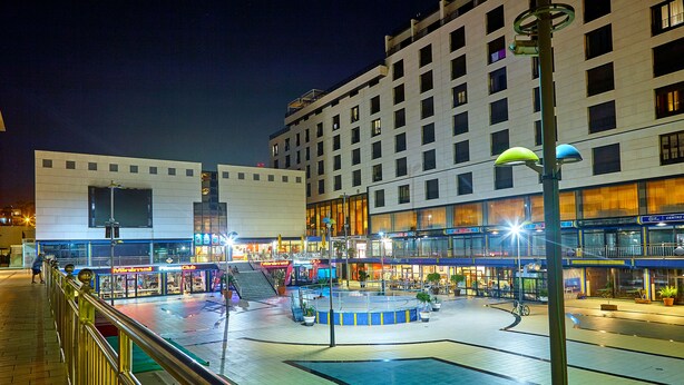 A nighttime urban square with a fountain, modern buildings, and a pedestrian walkway. - Hotel Zentral Center (Arona)
