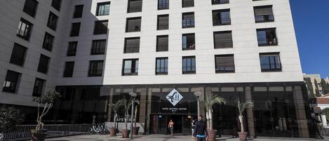 A modern hotel with a central entrance, multiple floors, and a clear sky.