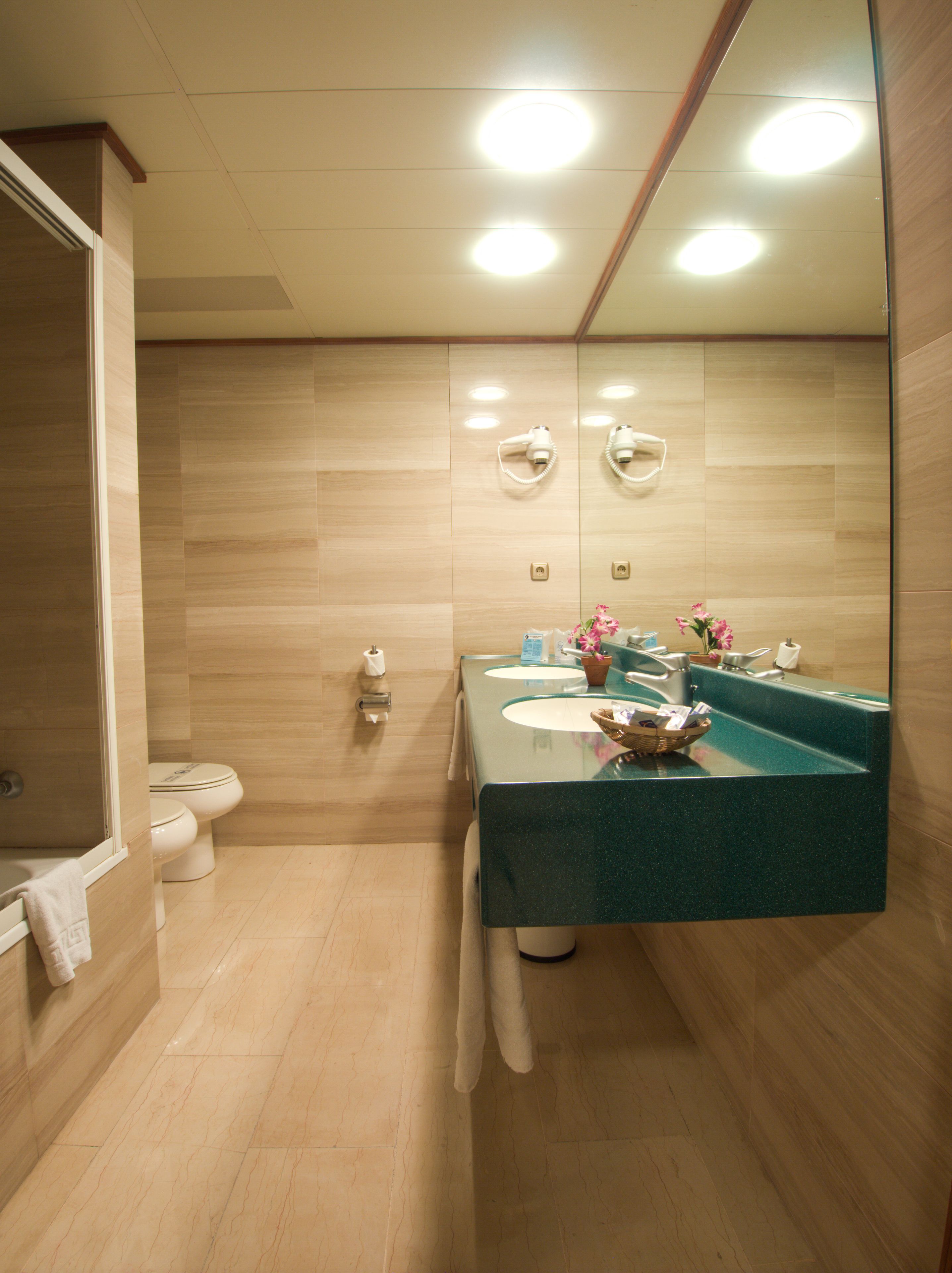 A modern bathroom with a large mirror, two sinks, and a shower area.