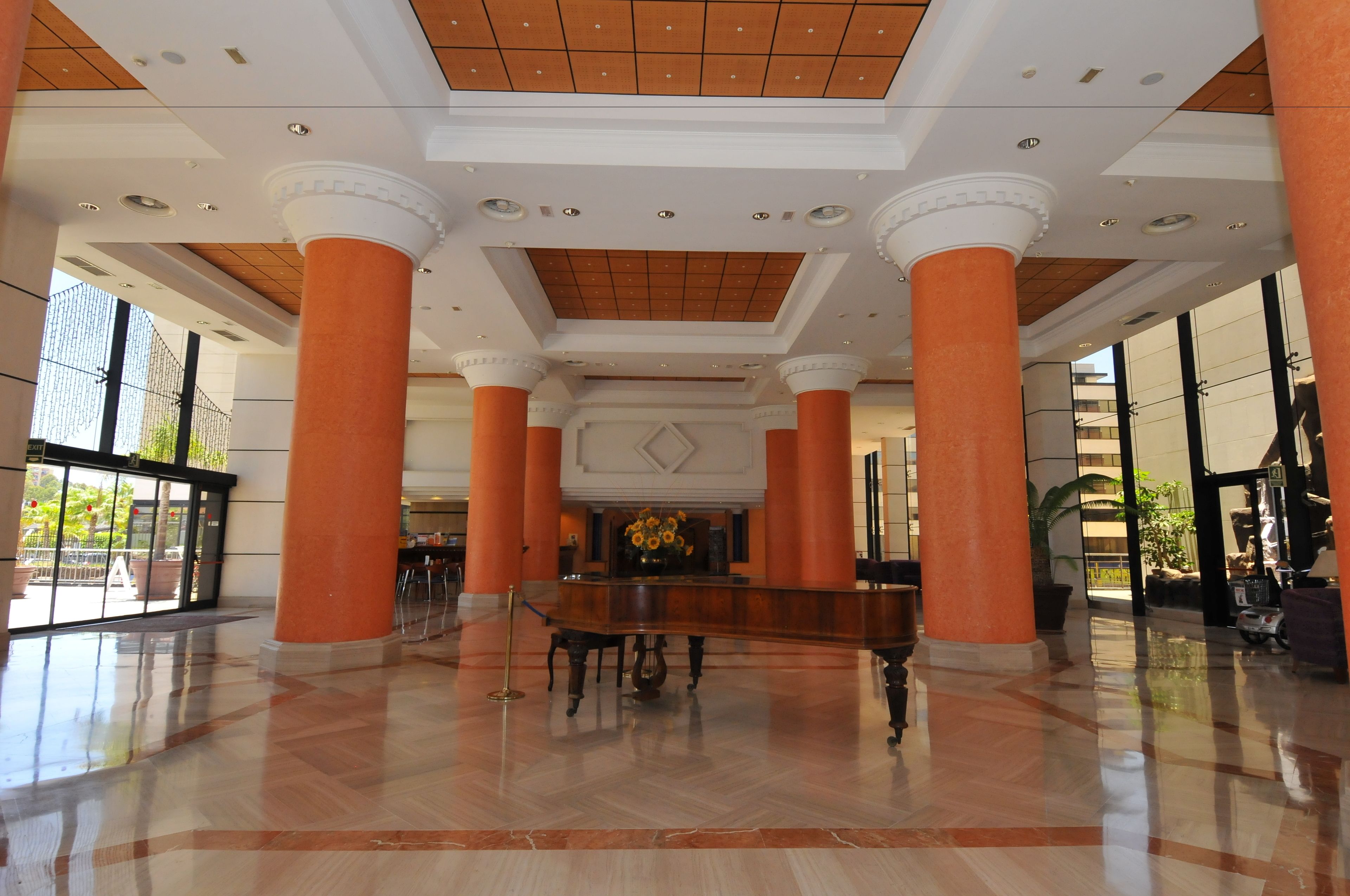A spacious lobby with high ceilings, large columns, and a grand piano.