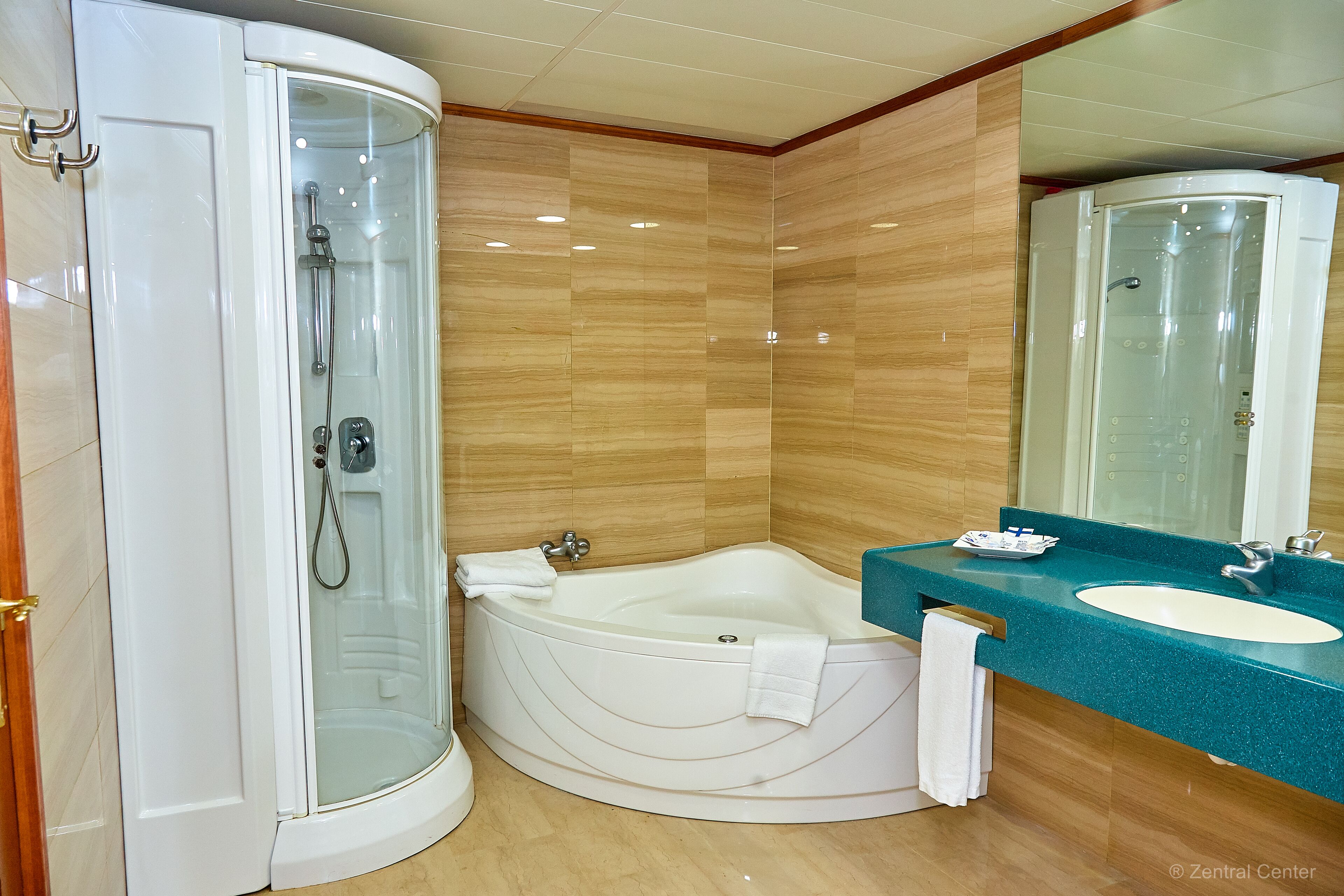Une salle de bain moderne dotée d’une douche à parois de verre, d’une baignoire sur pieds et d’un lavabo avec un plan de toilette de couleur turquoise.