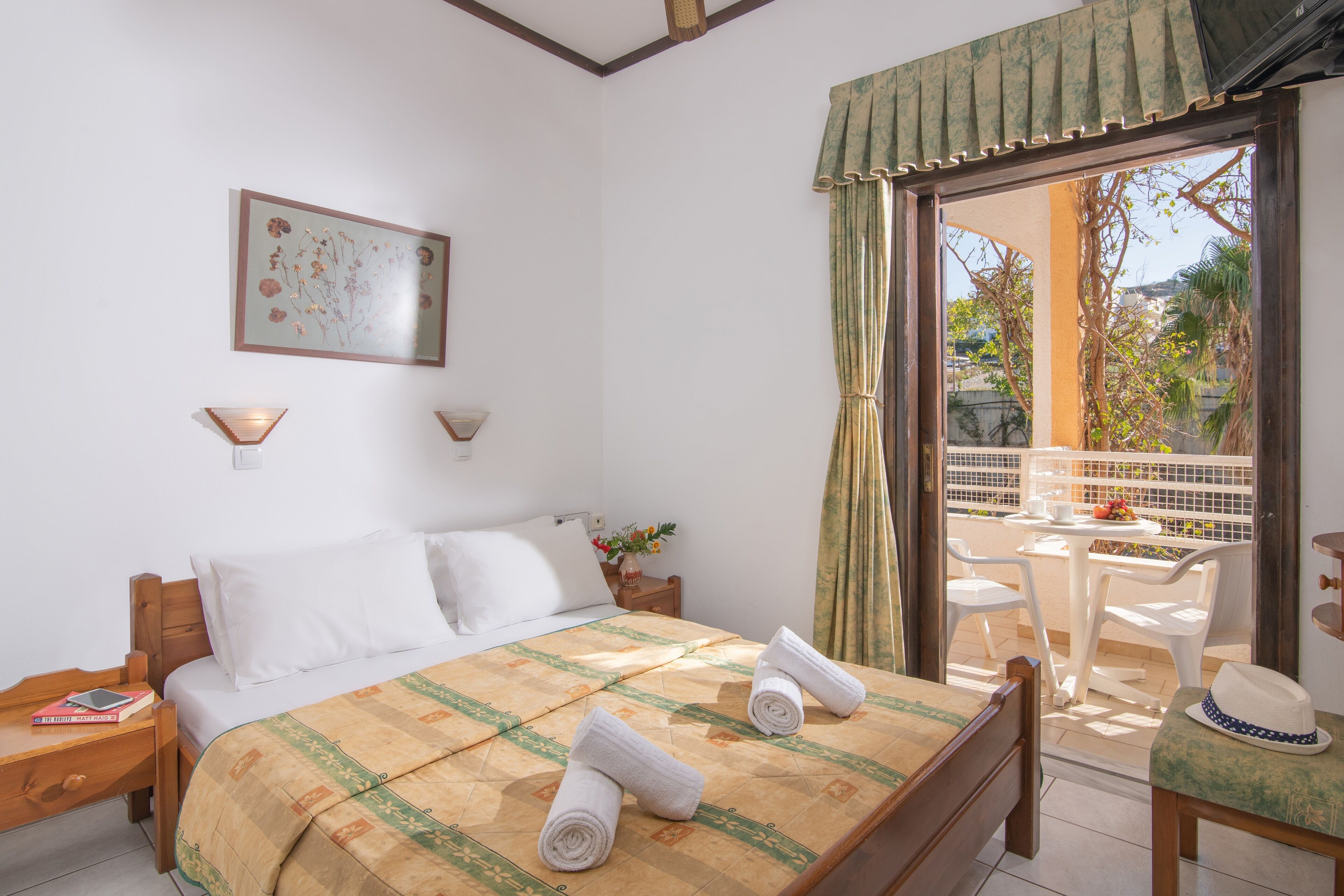 A bedroom with a bed, bedside tables, a window with curtains, and a view of the outside.