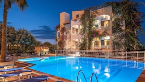 A swimming pool with lounge chairs and a building with balconies.