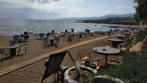 A beachside seating area with tables and chairs, overlooking the sea.