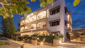 A multi-story hotel with a reception area, balconies, and outdoor seating.