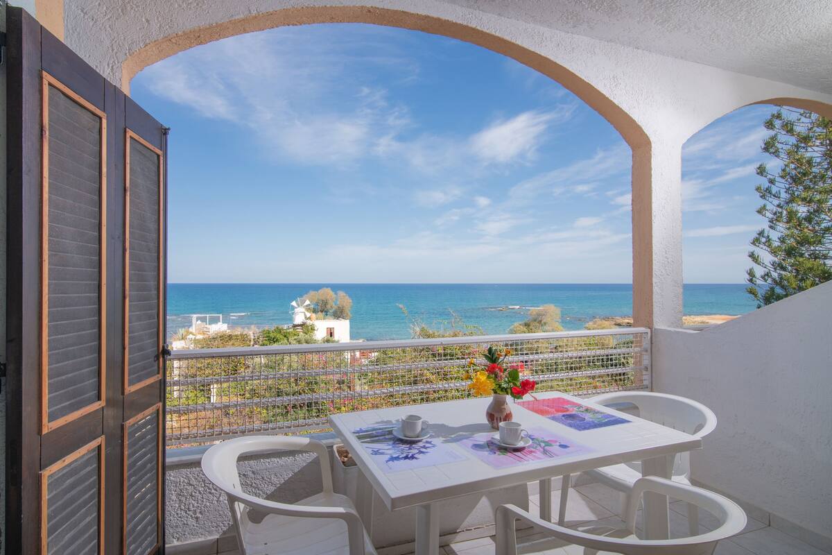 Un balcón con una mesa dispuesta para dos personas, con vistas a la costa.
