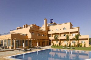 Ett hotell med en swimmingpool, utomhusplats och en skylt i form av bokstaven H på taket.
