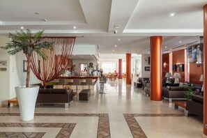 A spacious lobby with a reception desk, seating area, and a large potted plant. - Praia Sol (Vilamoura)
