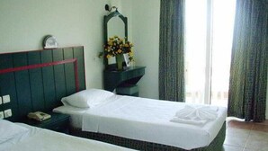 A hotel room with two beds, a nightstand, a mirror, and a vase with flowers. - Melodi (Marmaris)