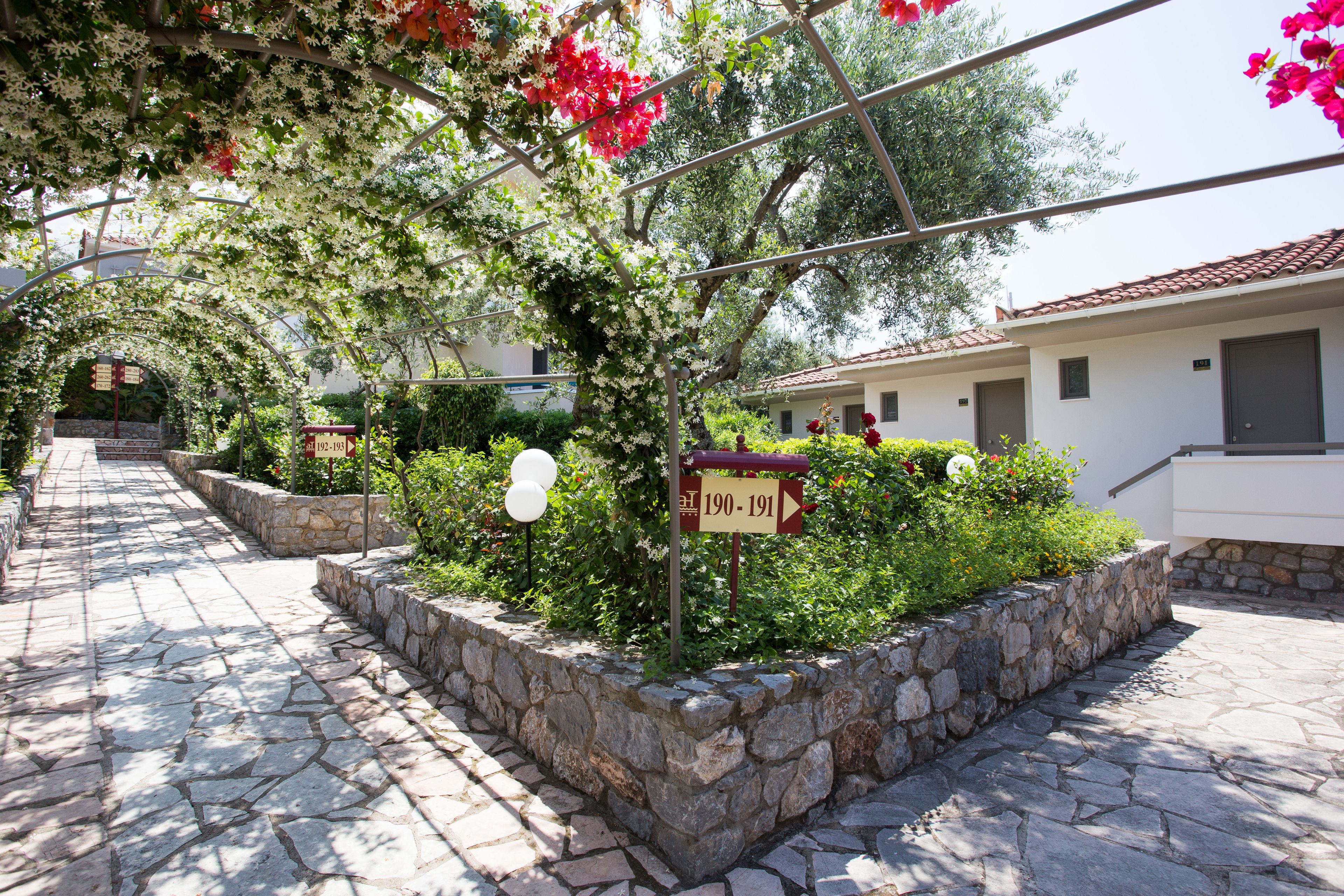 A stone-paved pathway leading to a building with a sign indicating room numbers 190-191.