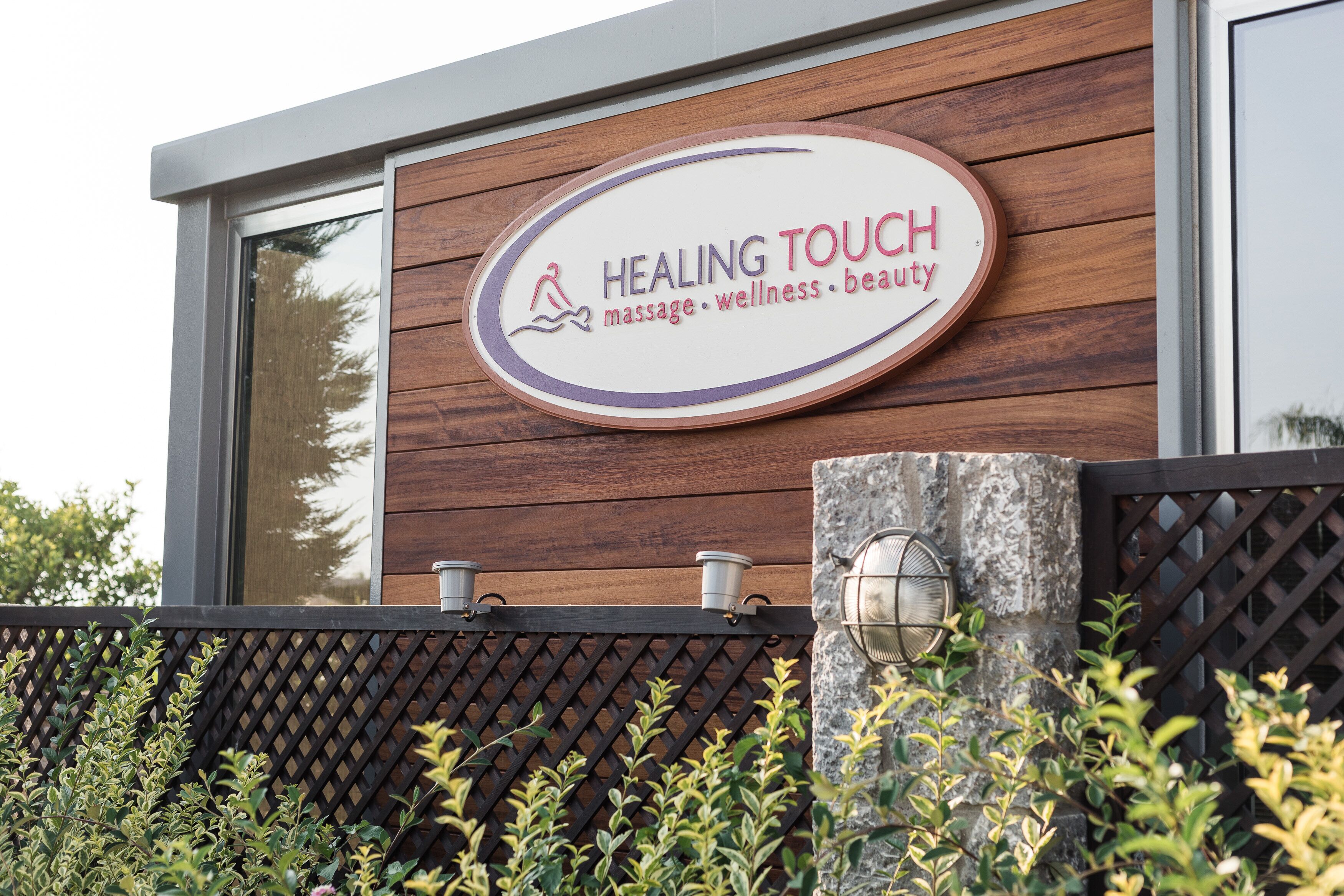 Letrero que dice 'Healing Touch', con un logotipo de una persona y una gota de agua, indicando servicios de masaje, bienestar y belleza.