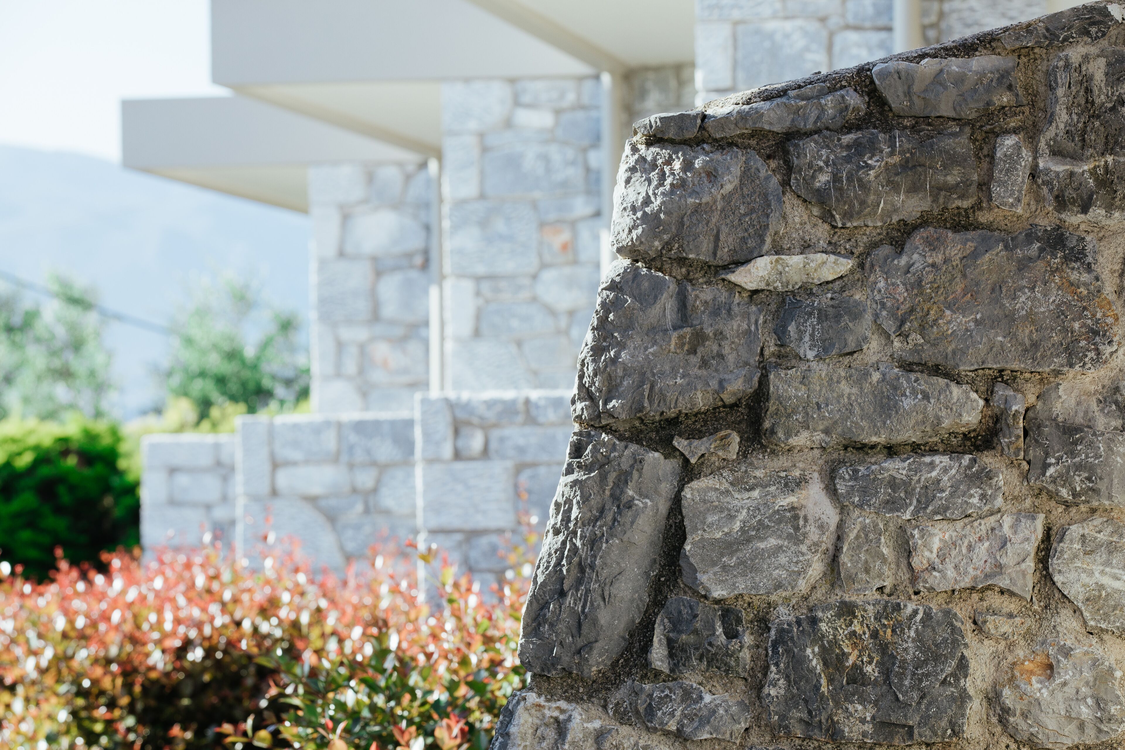A stone wall with a rough texture, part of a building's exterior.