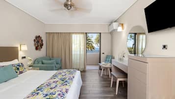 A hotel room with a bed, a desk, a chair, a television, and a balcony with curtains.