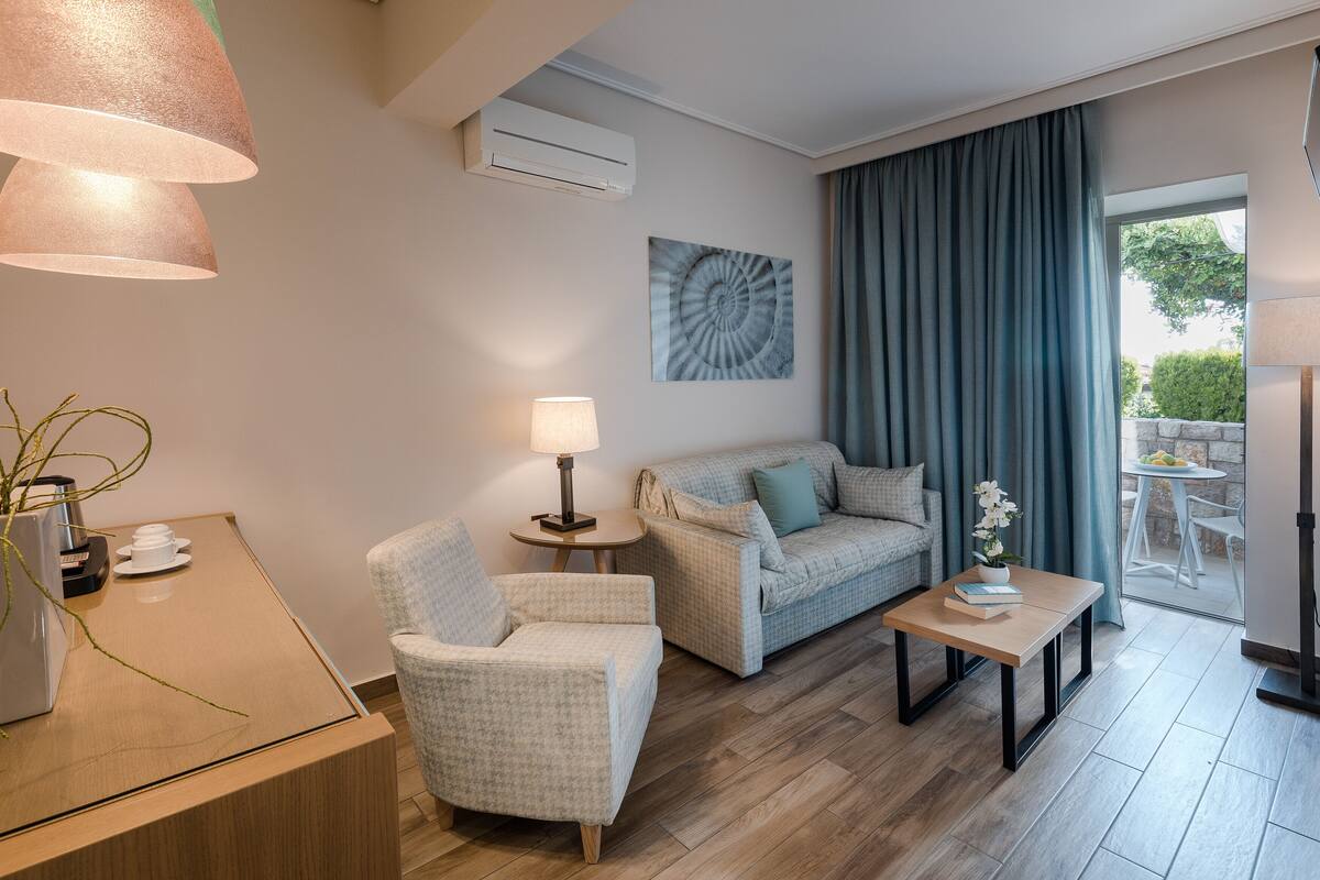 Et moderne hotelværelse med sofa, lænestol og et lille bord med lampe.