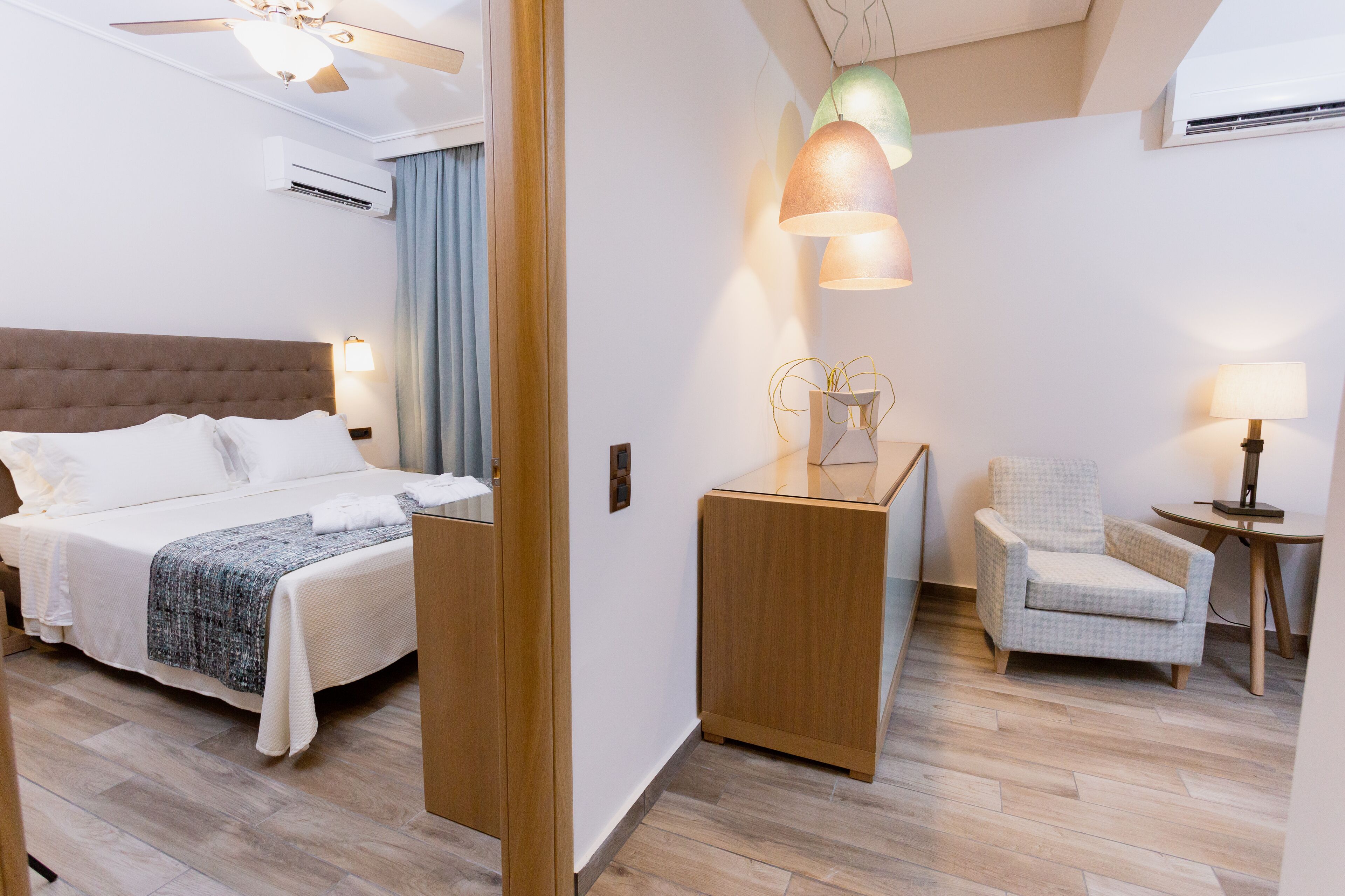 A hotel room with a bed, a desk, a chair, and a lamp.
